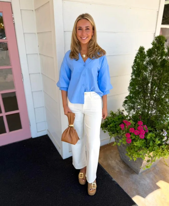 Woman styling white jeans with a light blue button-down shirt and brown leather accessories for an effortless casual look.