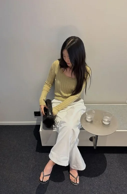 Woman wearing white jeans with an olive green top and brown accessories for an earthy casual outfit.