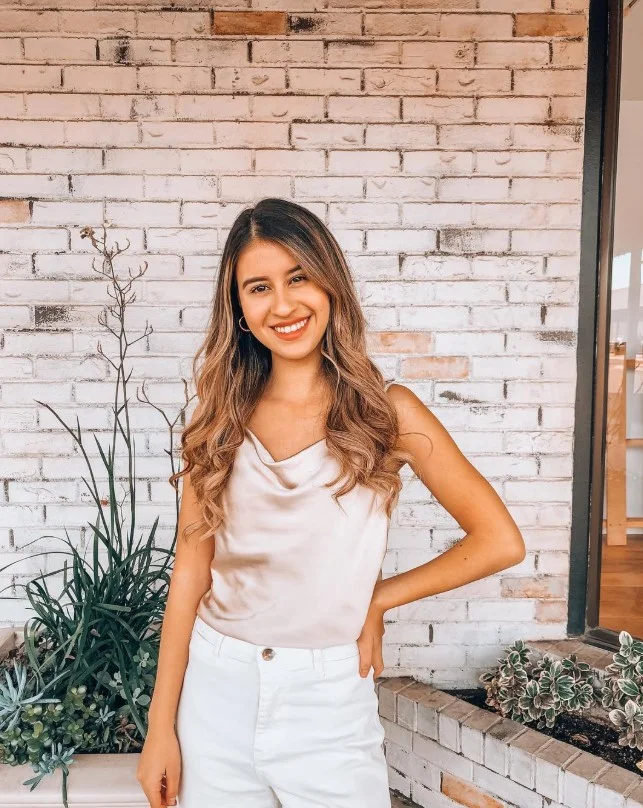 Woman wearing white jeans with a satin camisole and heels for an elegant date-night outfit.