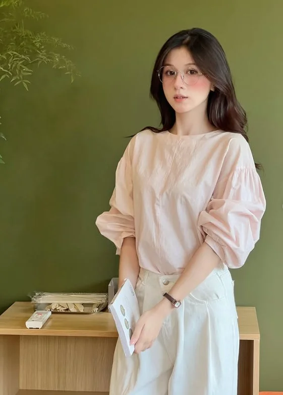 Woman wearing white jeans with a soft pink blouse and neutral shoes for a feminine brunch outfit.