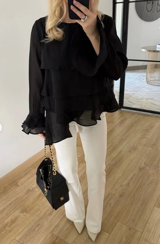 Woman wearing white jeans with a statement blouse and heels for an elegant dinner-ready outfit.