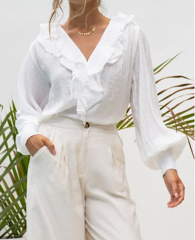 Woman wearing white jeans with a textured white top and neutral leather accessories for a chic monochromatic outfit.