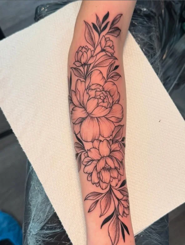 Black-and-grey floral forearm tattoo with detailed shaded flowers