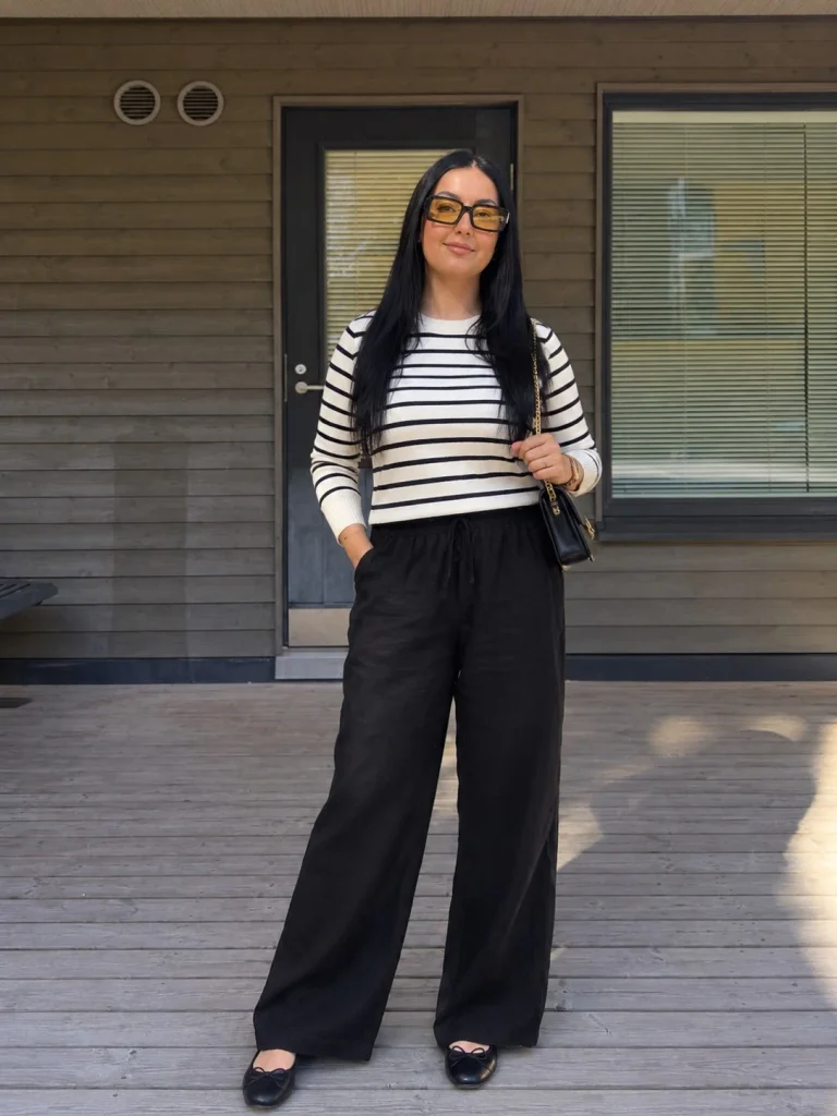 Woman wearing black linen pants with a striped knit top and neutral ballet flats