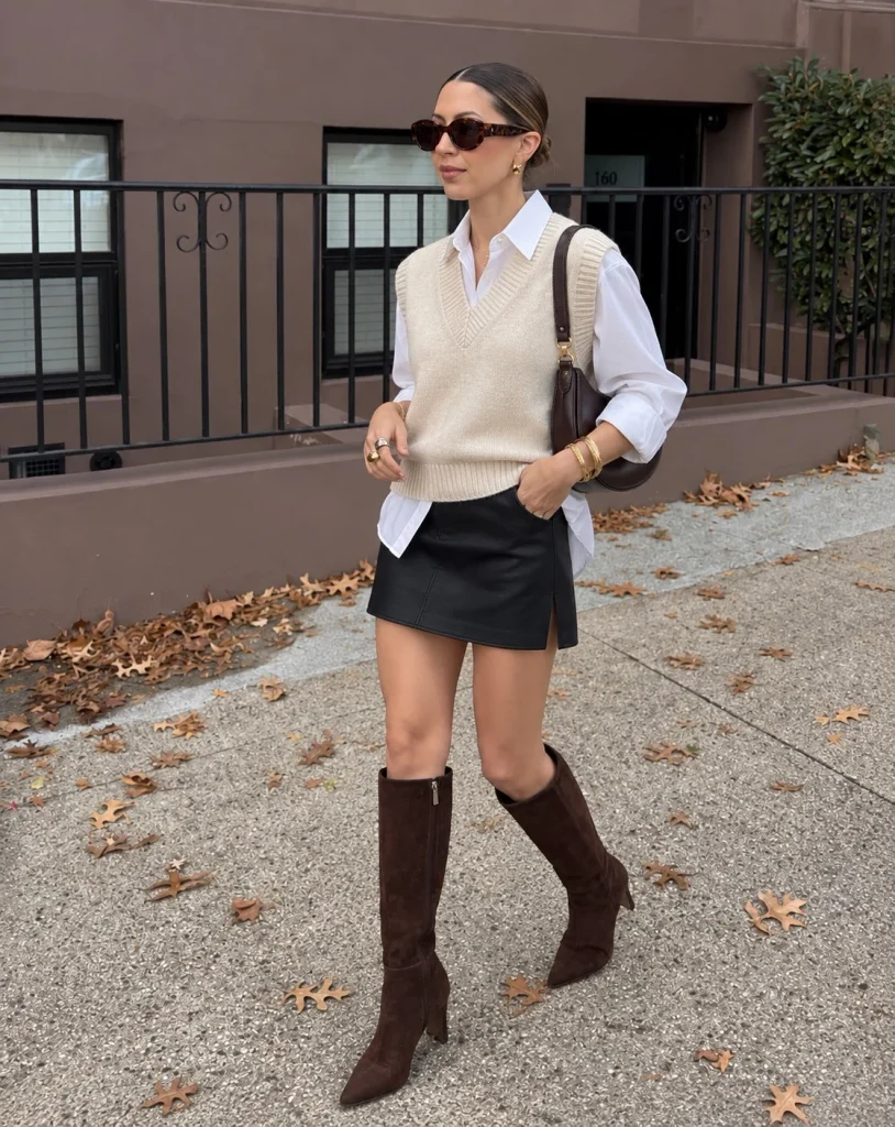 Black mini skirt with knit vest and knee-high boots