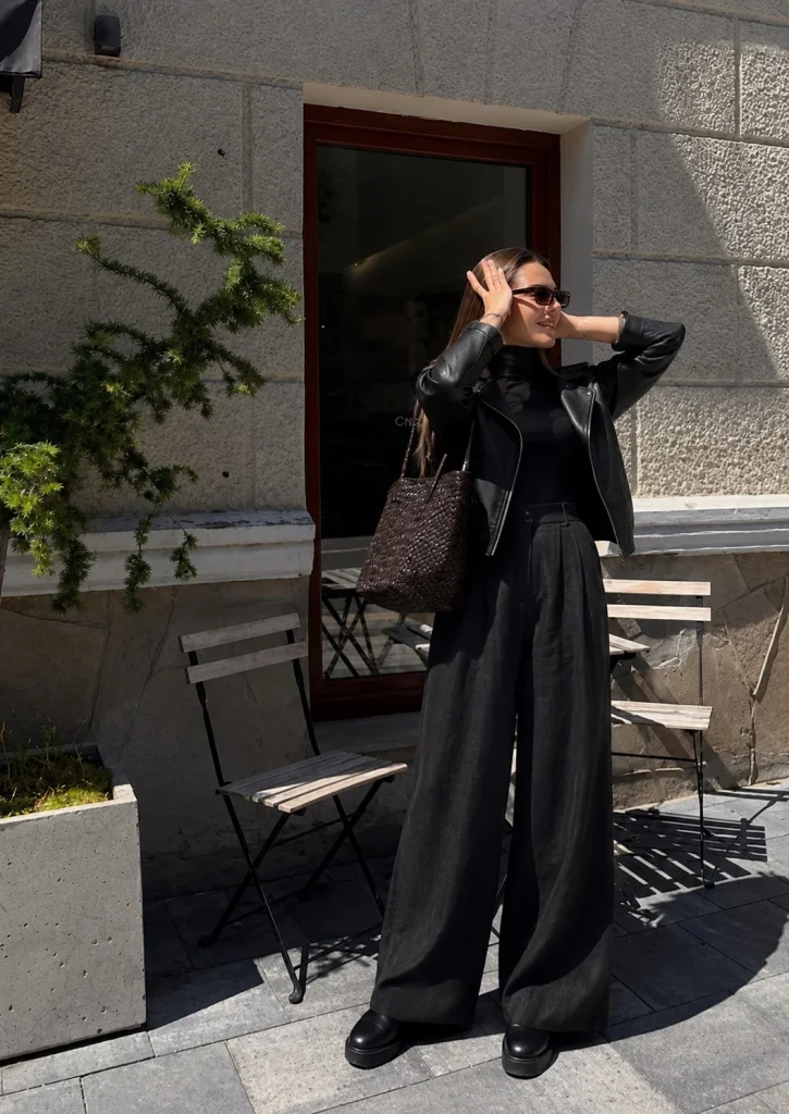 Woman wearing wide-leg black linen pants with a black turtleneck, leather jacket