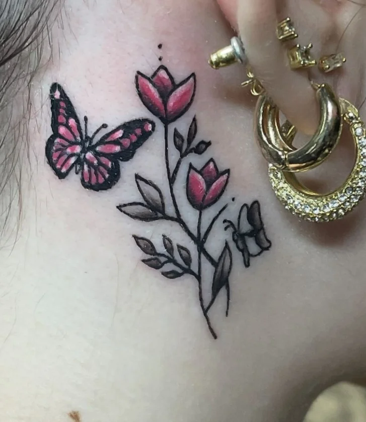 Butterfly and flower behind the ear tattoo with a delicate feminine design
