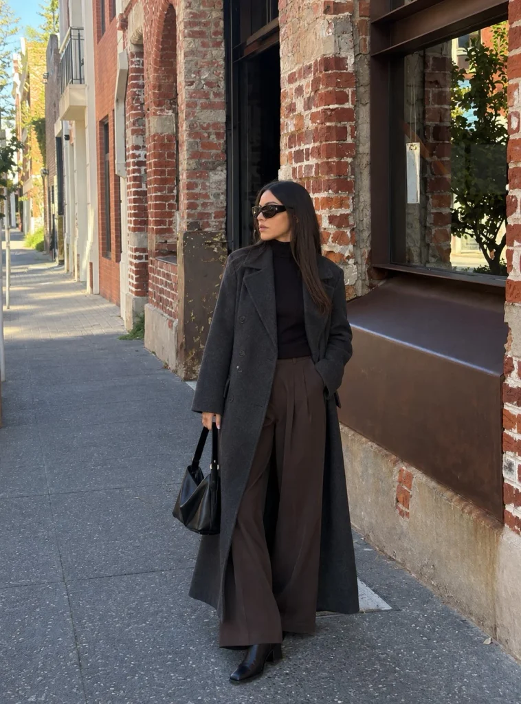 Woman wearing dark wide-leg trousers with a long wool coat and ankle boots
