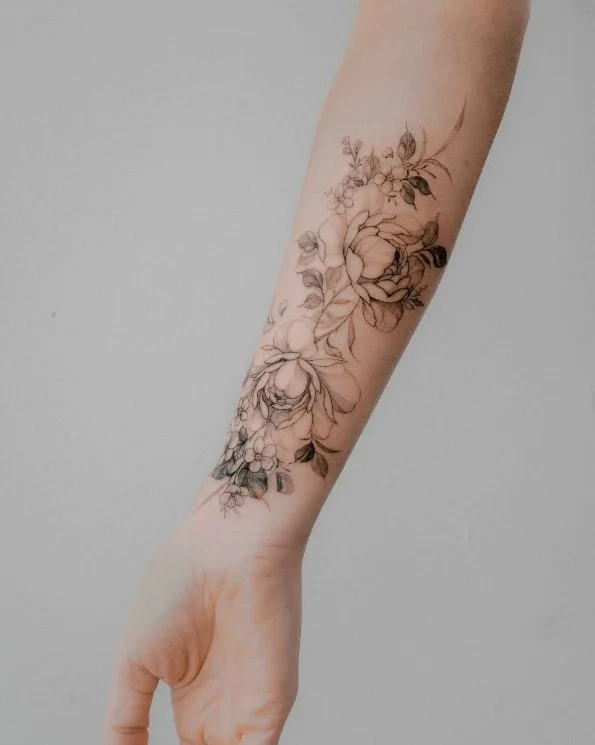 Floral cover-up forearm tattoo using flowers and foliage to create a new design