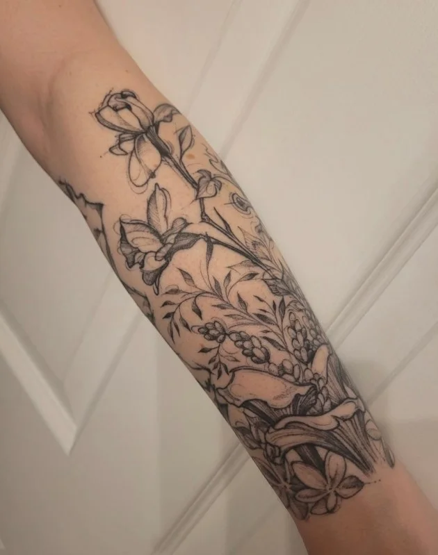 Floral half-sleeve forearm tattoo with connected flowers and botanical details