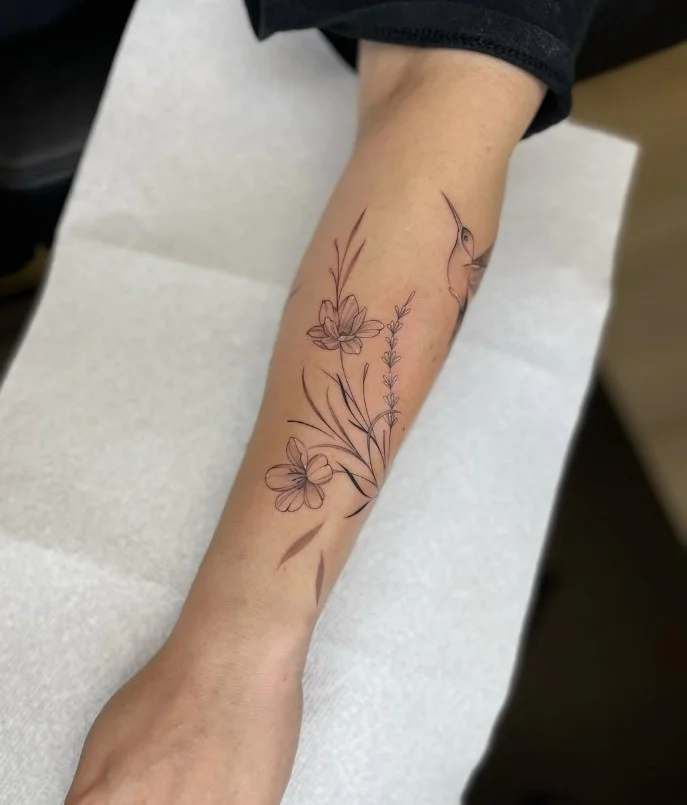 Floral vine forearm tattoo with flowers and leaves flowing along the arm