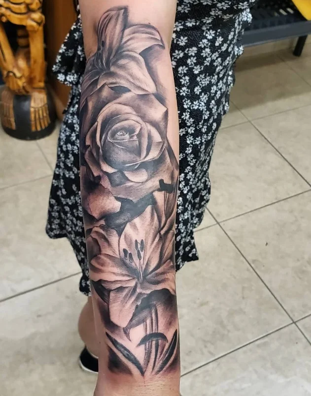 Floral wrist-to-elbow tattoo featuring flowers and foliage flowing along the forearm