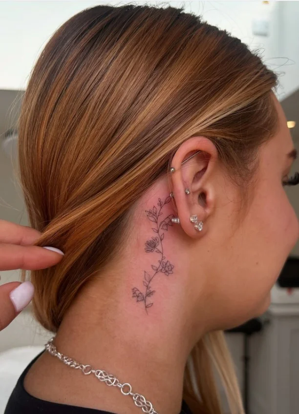 Simple flower behind the ear tattoo for women with a delicate floral design