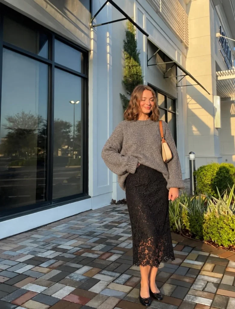 Woman wearing a gray oversized sweater with a black lace midi skirt and ballet flats
