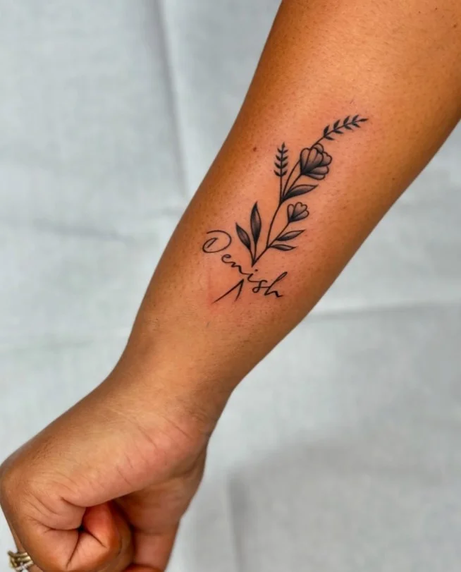 Meaningful floral forearm tattoo featuring flowers with personalized lettering