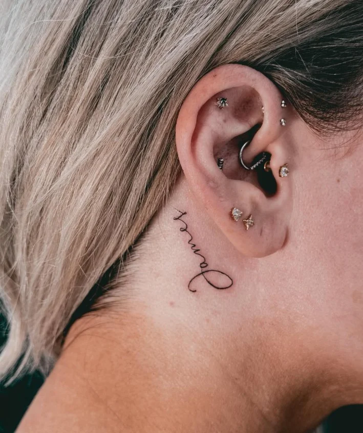 Meaningful word behind the ear tattoo with delicate lettering