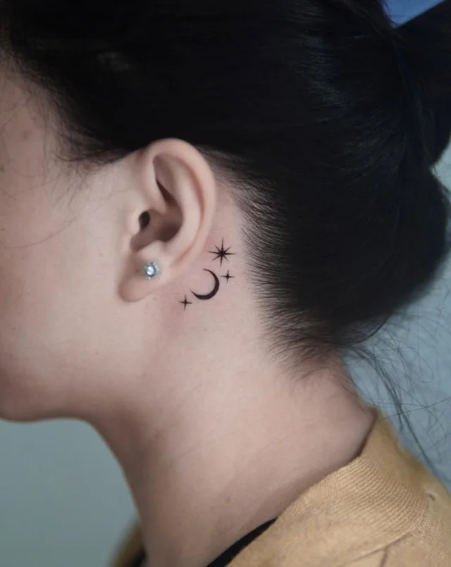 Moon and stars behind the ear tattoo with a small celestial design
