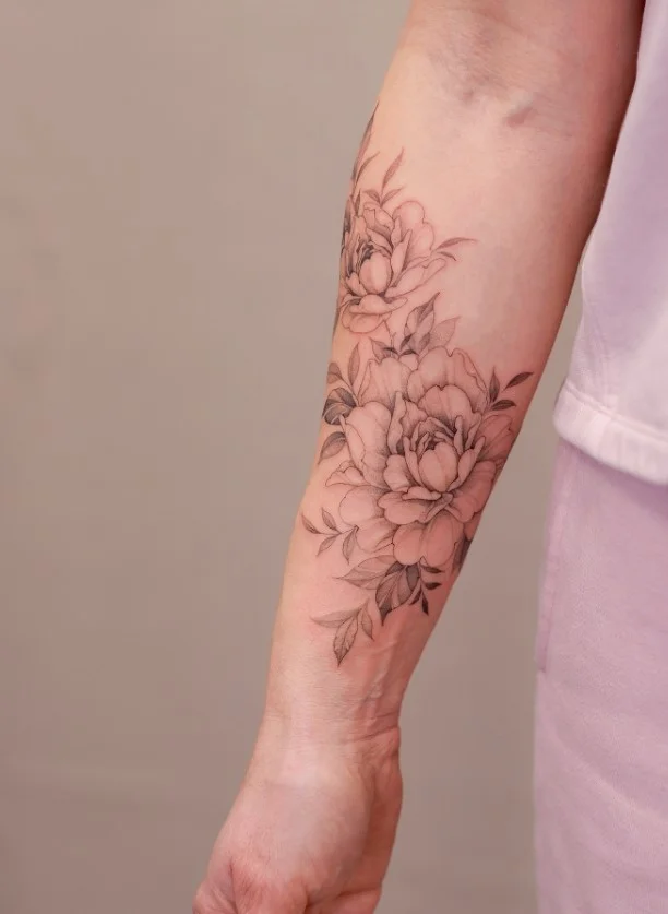 Peony forearm tattoo featuring a detailed layered flower