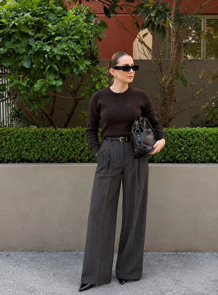 Woman wearing pinstripe wide-leg trousers with a fitted sweater and pumps