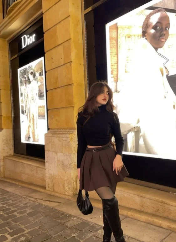 Woman wearing pointed-toe knee-high boots with a mini skirt and tights