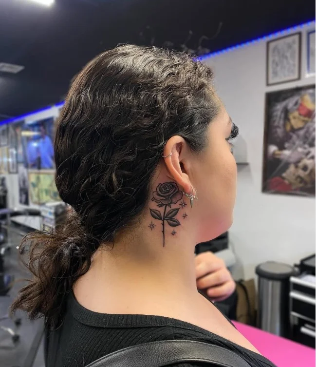 Small rose behind the ear tattoo for women with a delicate fine-line design