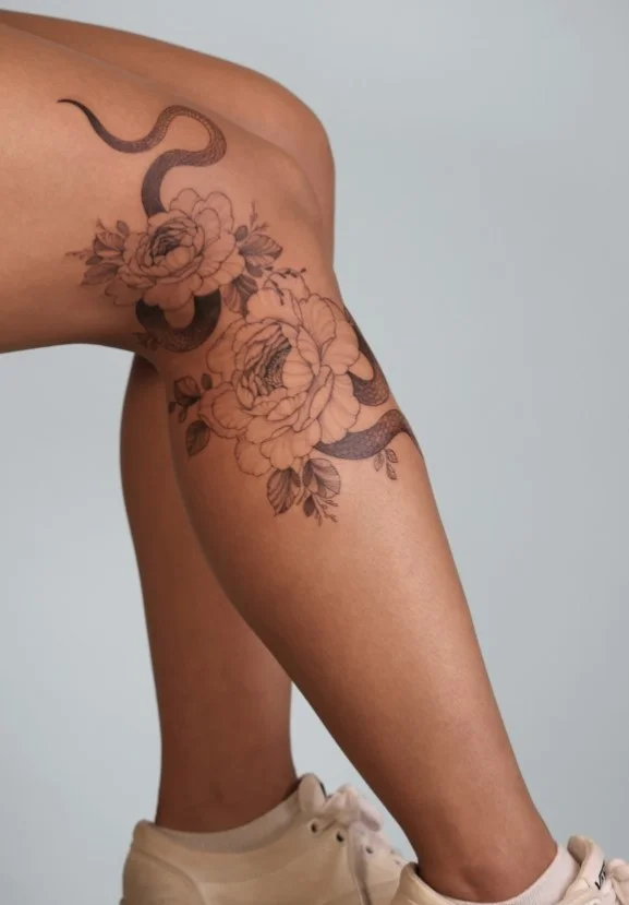 Snake and ornamental flowers half leg tattoo for women