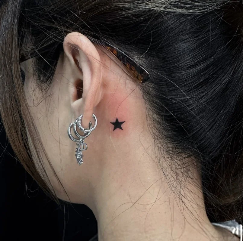 Tiny star behind the ear tattoo with a simple minimalist design
