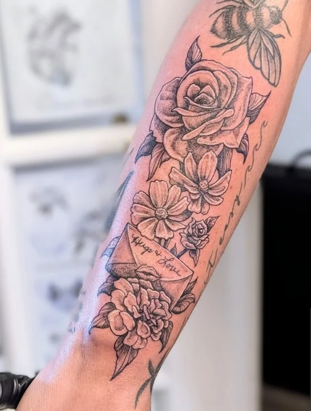 Vertical floral bouquet forearm tattoo with flowers arranged along the arm