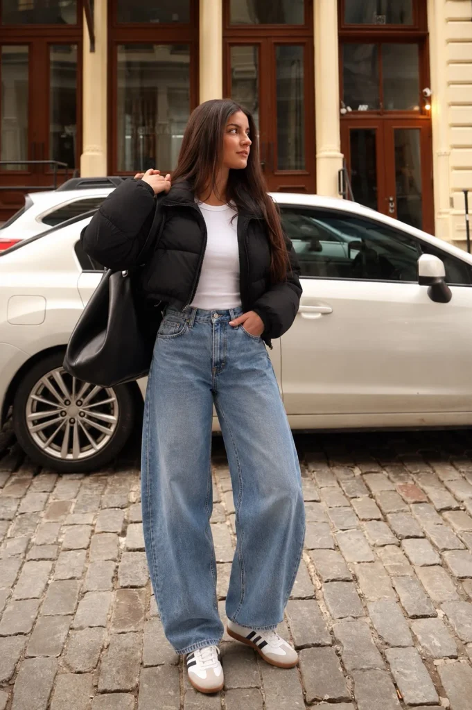 Black cropped puffer jacket with barrel-leg jeans, fitted white top and retro sneakers