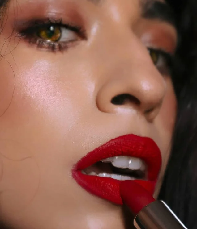 Woman wearing cool blue-based red lipstick with softly defined eyes on brown skin
