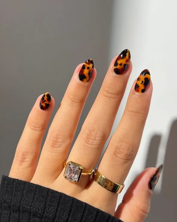 Tortoiseshell acrylic nails featuring layered amber, caramel, and dark brown patterns.