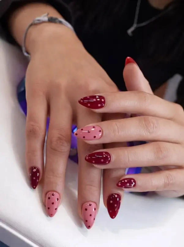 Burgundy and blush pink nails with contrasting polka dots on alternating nails