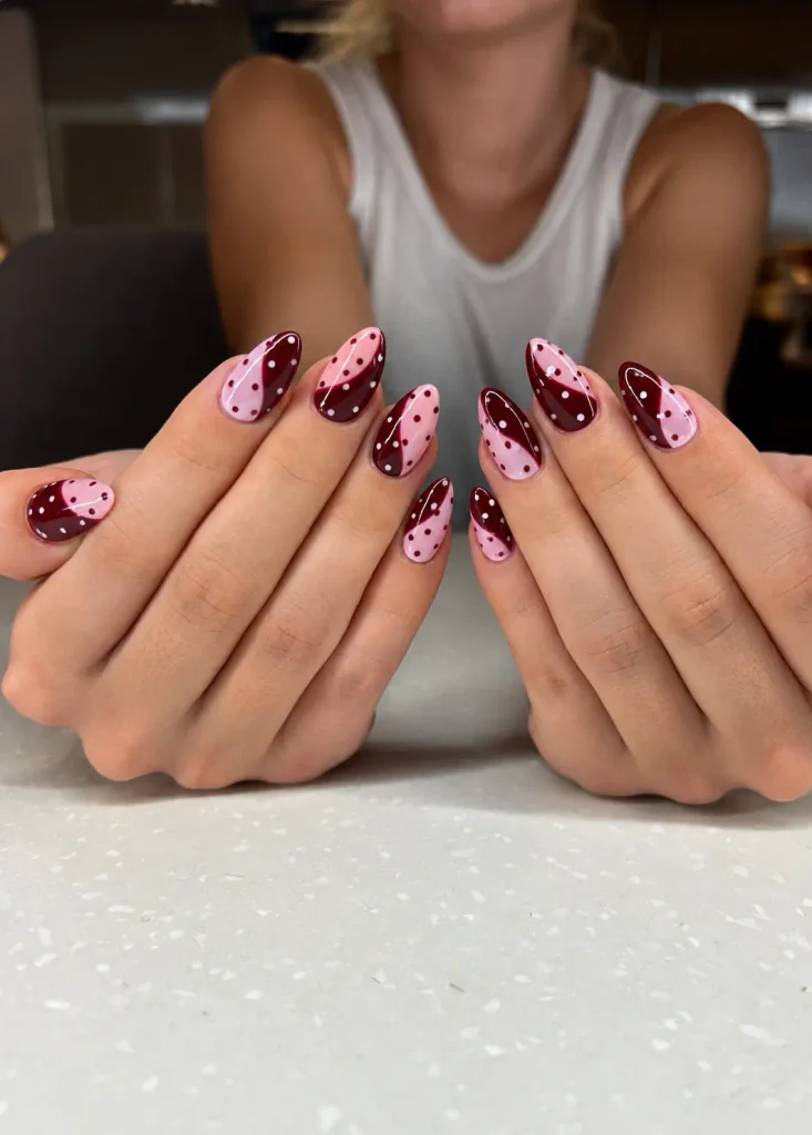Burgundy and pink color-block nails with contrasting polka dot designs
