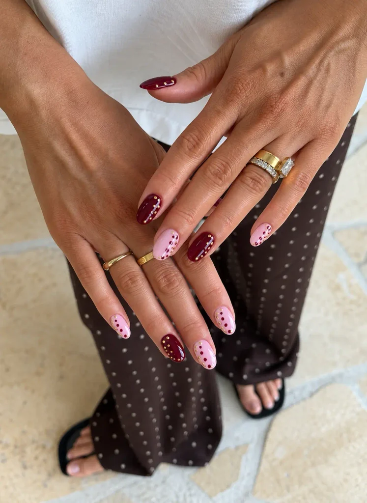 Burgundy and pink polka dot nails accented with small gold details