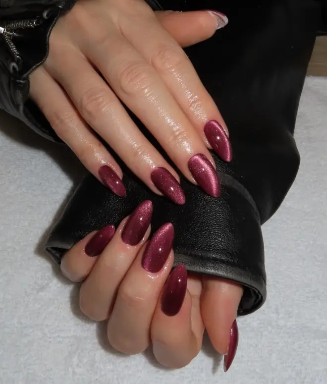 Burgundy cat-eye acrylic nails with a reflective magnetic shimmer and velvet-like finish.