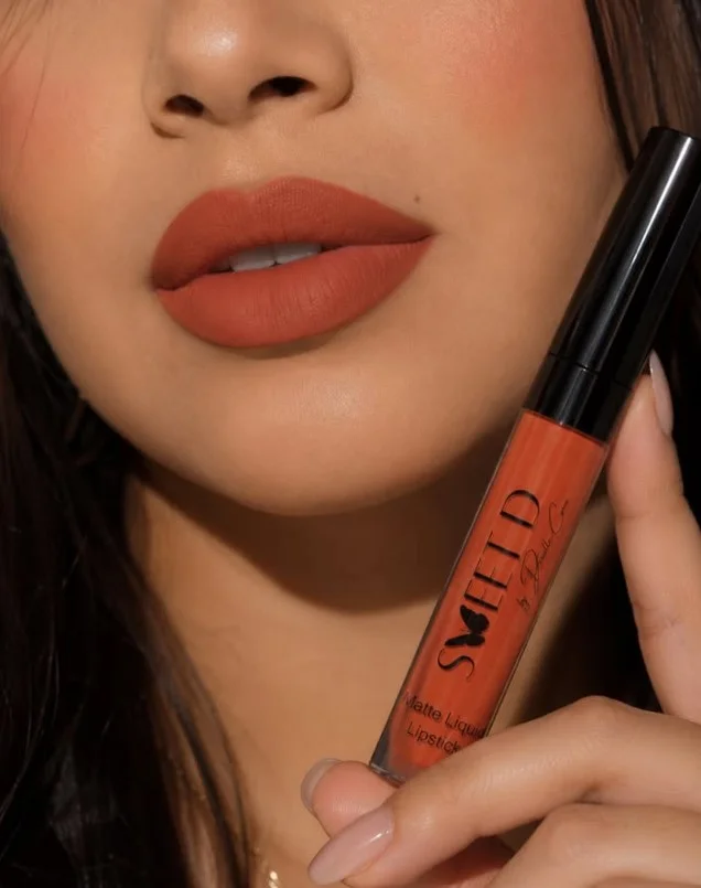 Woman wearing bold burnt orange lipstick with warm brown undertones on brown skin
