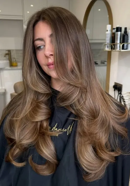 Dark brown hair with caramel balayage ribbons creating warm brown-gold dimension and blended highlights