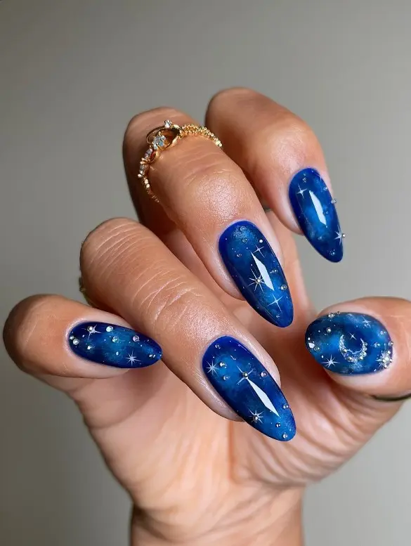 Deep navy acrylic nails decorated with small silver stars and crescent moon nail art.