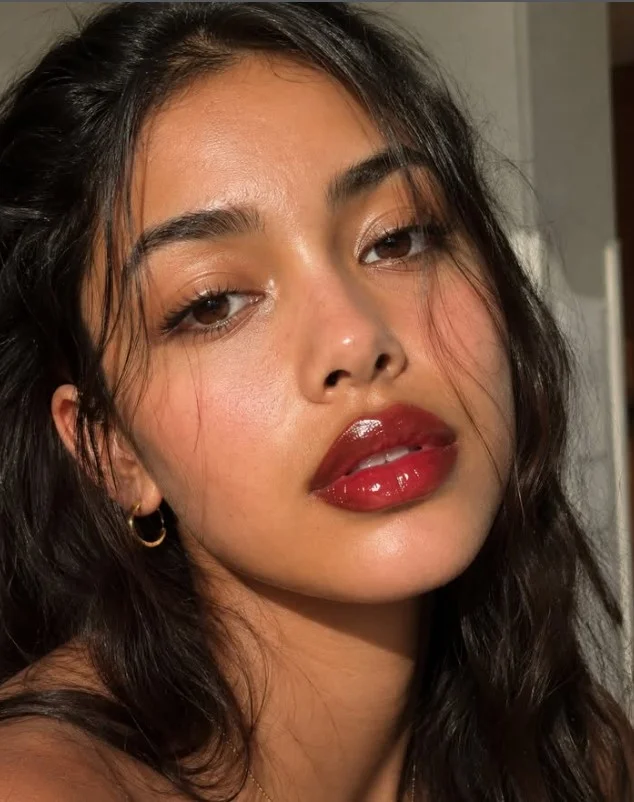 Woman wearing bright cherry red lipstick with a vibrant classic red finish on brown skin