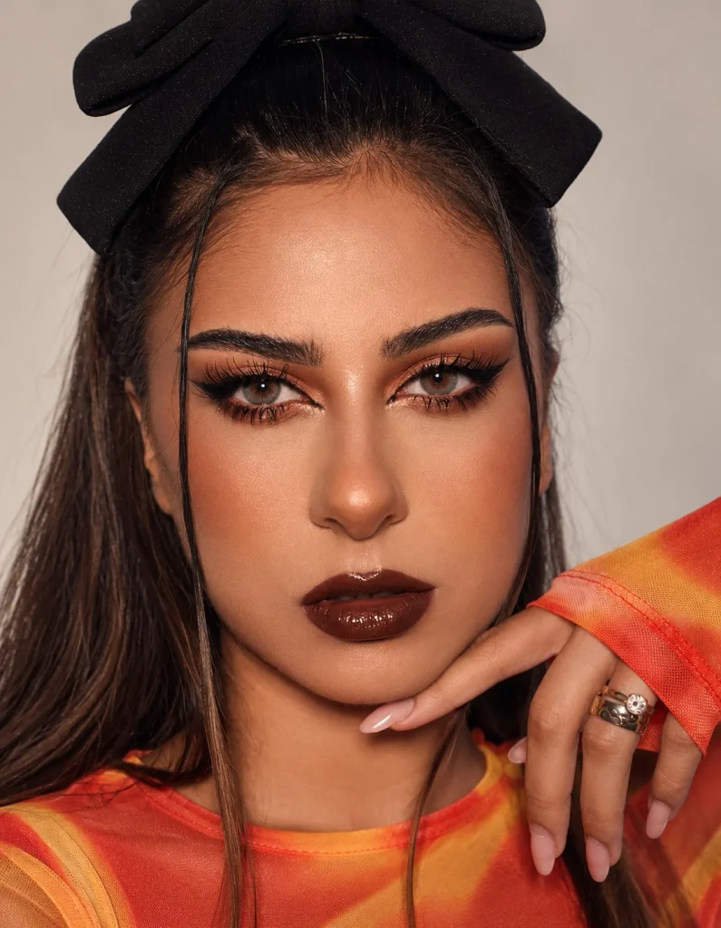 Woman wearing rich chocolate brown lipstick with warm brown tones on brown skin