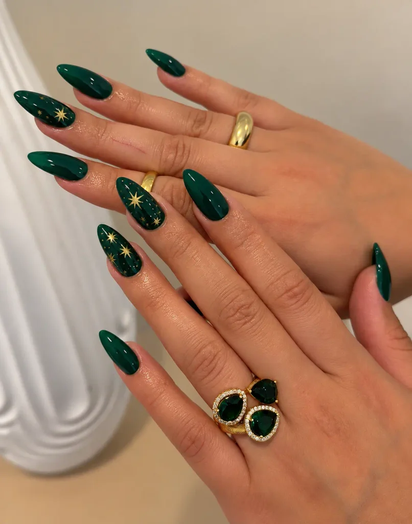 Dark green Christmas nails decorated with tiny scattered gold stars on accent nails