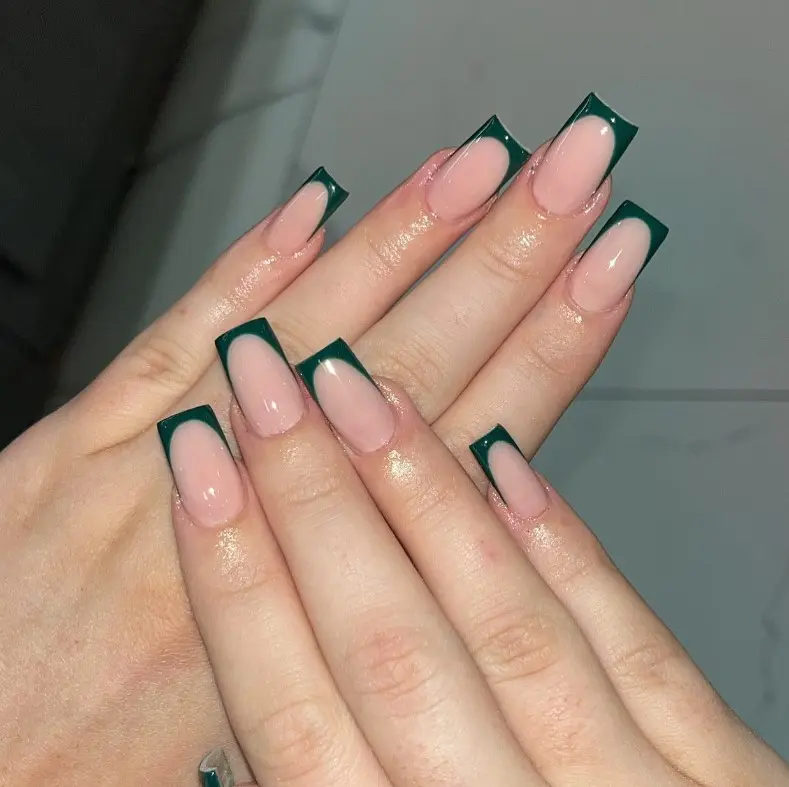 Dark green French tip nails with narrow evergreen tips over a sheer nude or milky base