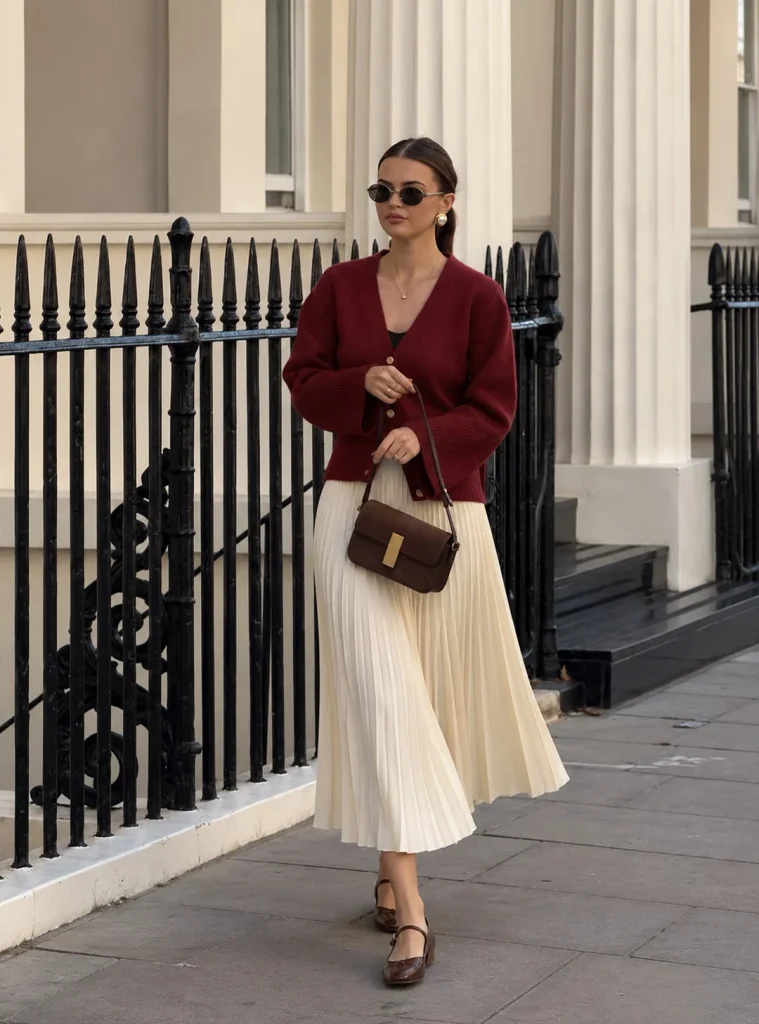 Dark red cardigan paired with a cream pleated midi skirt and chocolate brown Mary Jane flats