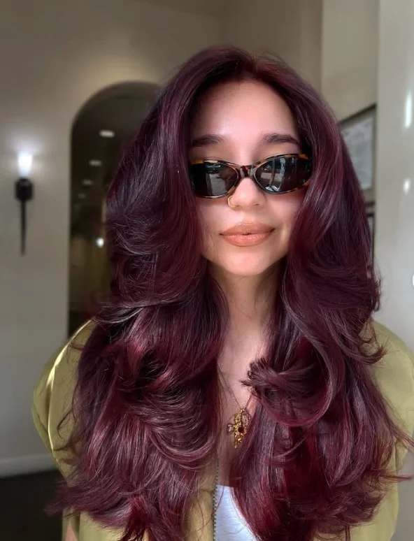 Deep burgundy hair with rich wine-red tones on olive skin