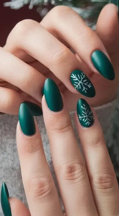 Deep green Christmas nails decorated with delicate white snowflakes and fine dotted details