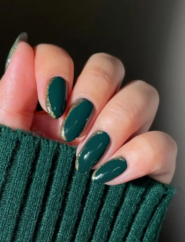 Forest green Christmas nails with irregular gold foil flakes concentrated near the tips and sides