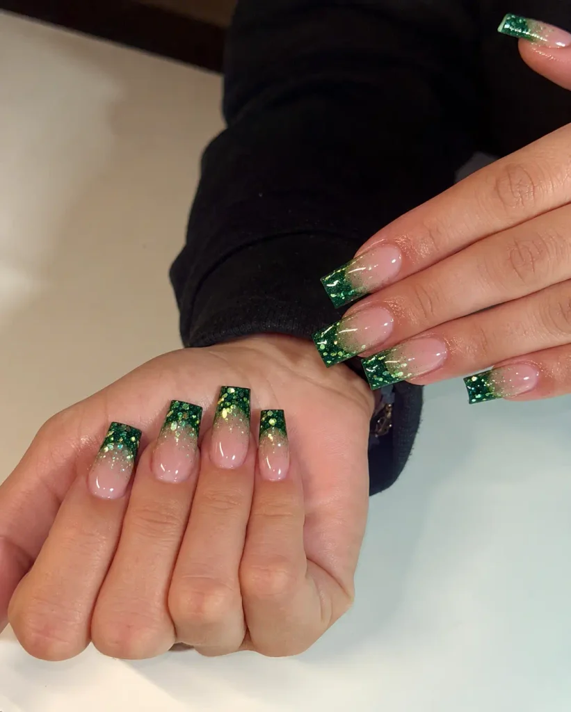 Green glitter Christmas ombre nails with sparkling tips that gradually fade into a nude base