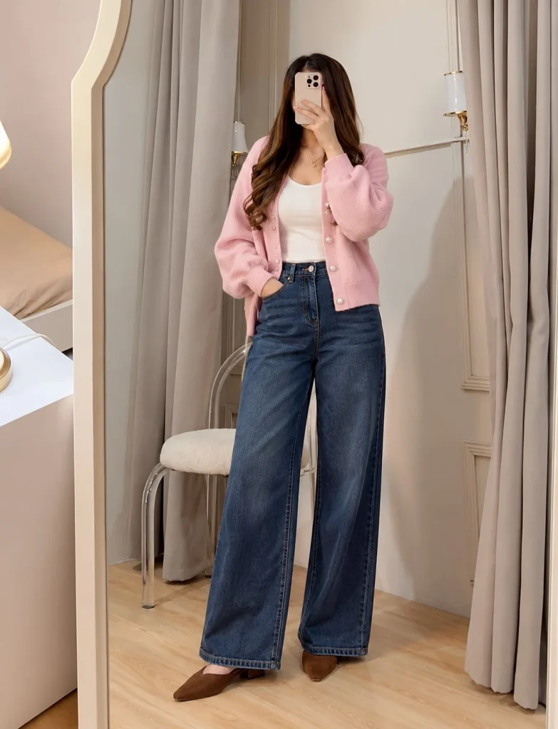 Light pink cardigan with dark-wash wide-leg jeans, white fitted top, and chocolate brown suede mules