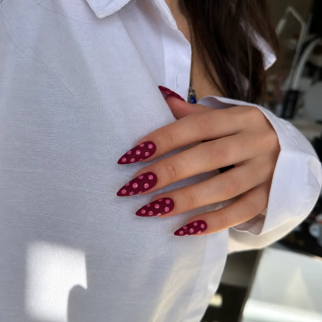 Matte burgundy nails decorated with glossy pink polka dots