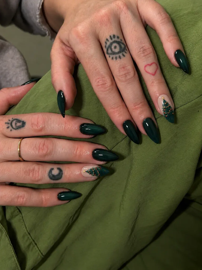 Dark green Christmas manicure with miniature green tree nail art and tiny red or gold ornaments on a pale accent nail